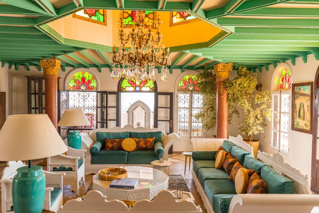 a living room with a green couch and a chandelier at Lalla Soulika in Tangier