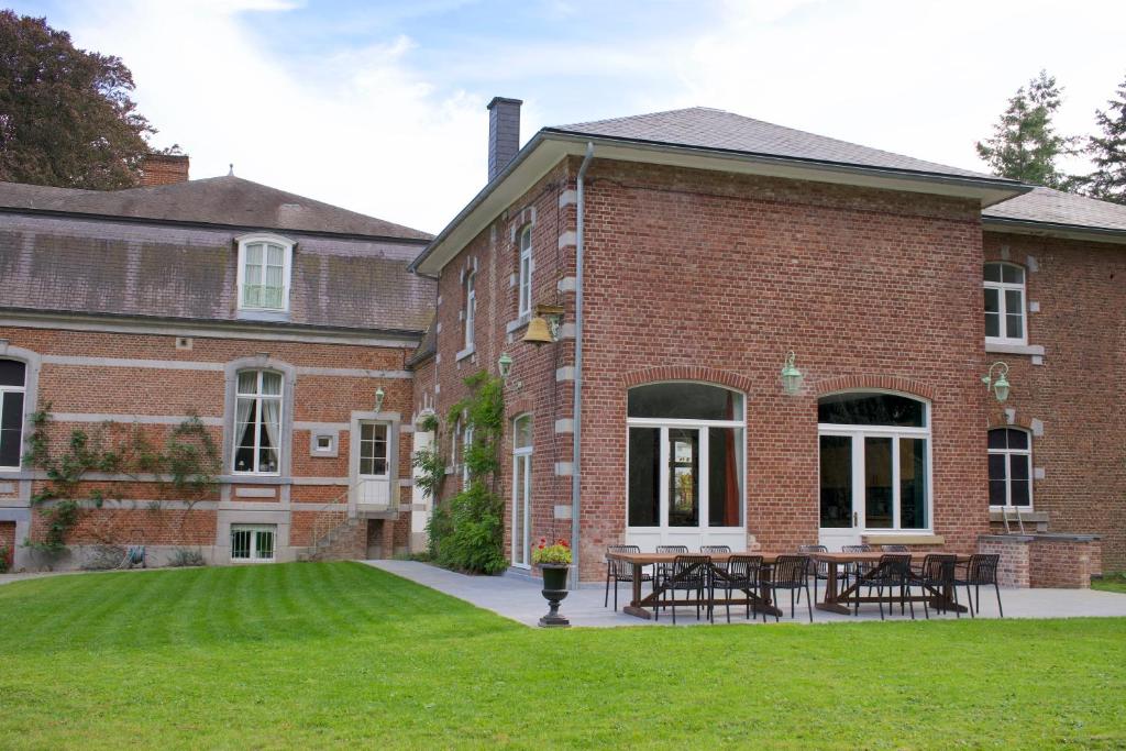 een bakstenen gebouw met tafels en stoelen op de binnenplaats bij Les Hys de Verdenne in Marche-en-Famenne