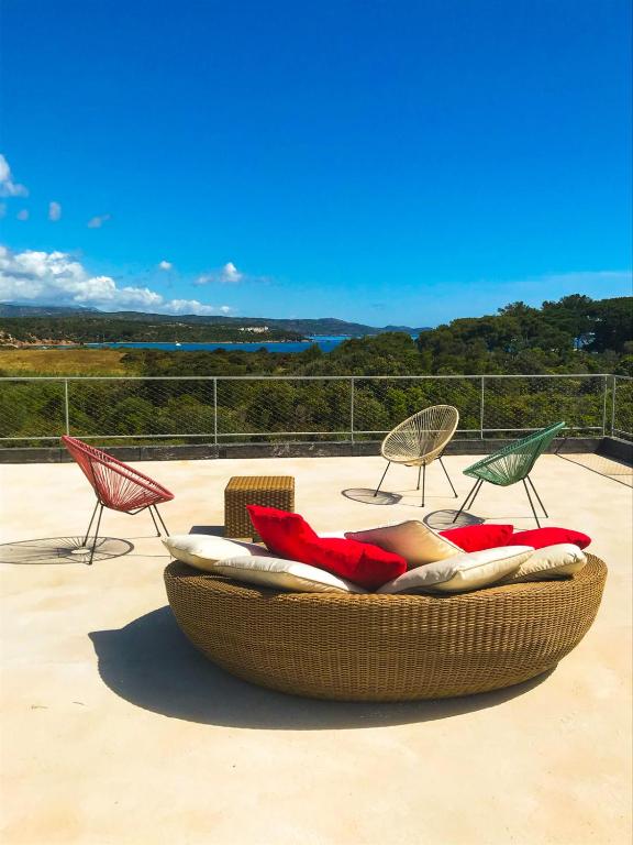 une chaise en osier et des chaises assises sur une terrasse dans l'établissement Villa esprit moderniste avec piscine, à Bonifacio