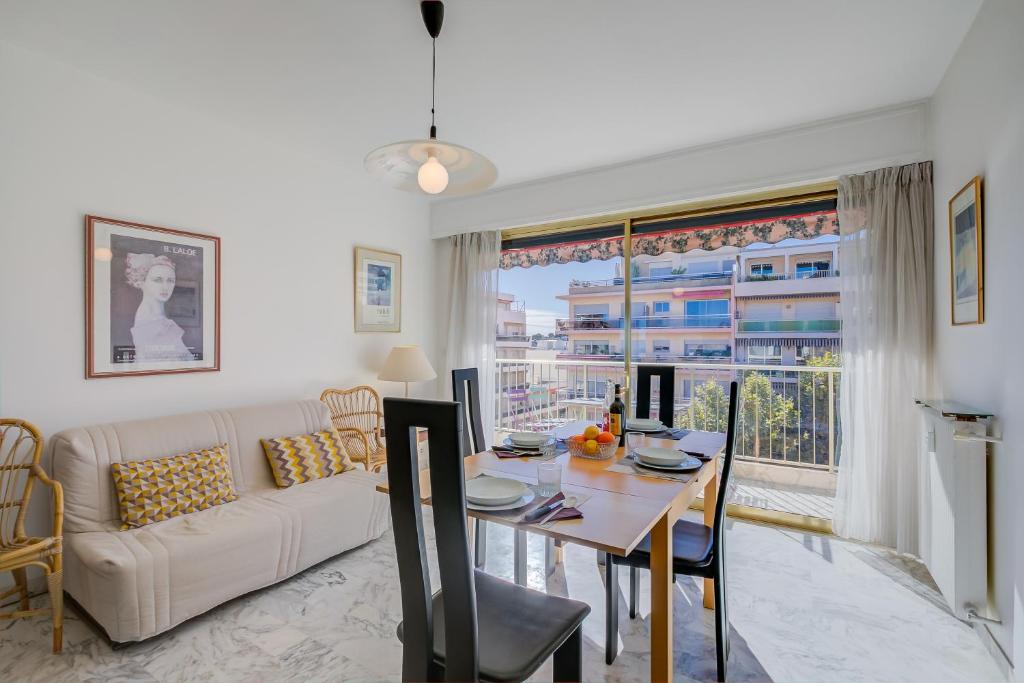 ein Wohnzimmer mit einem Tisch, einem Sofa und einem Fenster in der Unterkunft Appartement Le Fabiola - Happy Rentals in Antibes