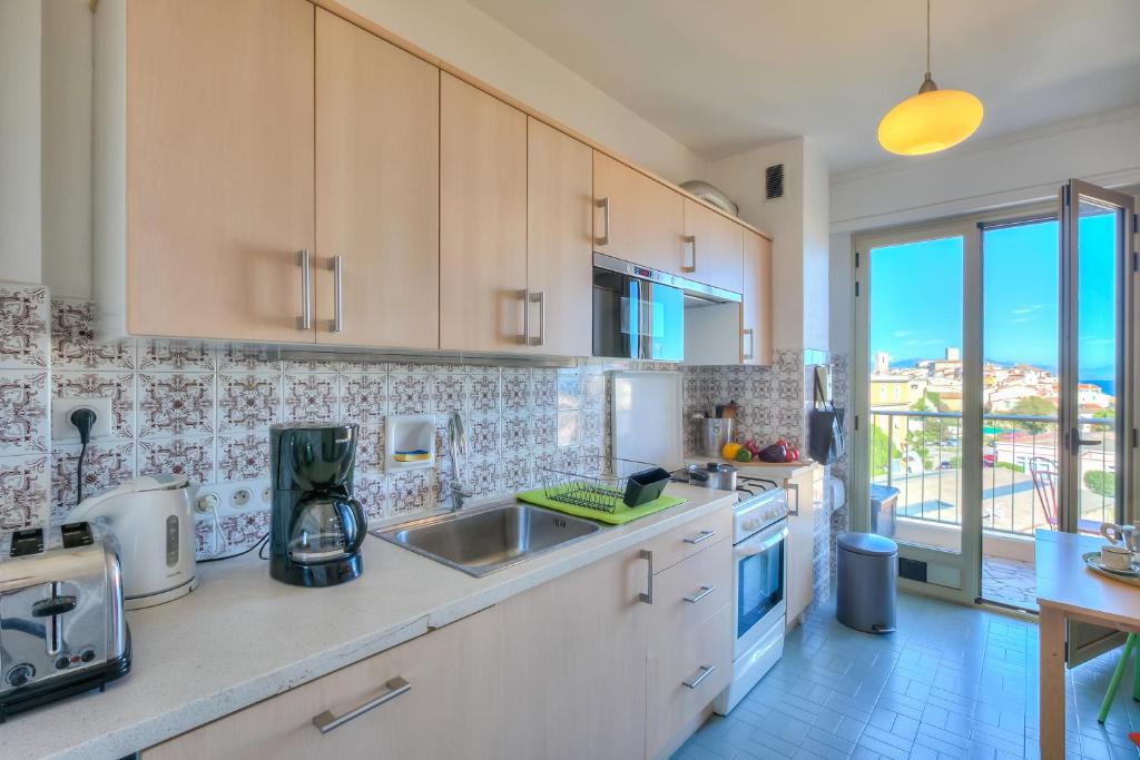eine Küche mit weißen Schränken und einem großen Fenster in der Unterkunft Appartement Le Fabiola - Happy Rentals in Antibes