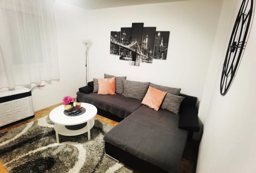 ein Wohnzimmer mit einem schwarzen Sofa und einem Tisch in der Unterkunft Privatni Smještaj Harmony in Osijek