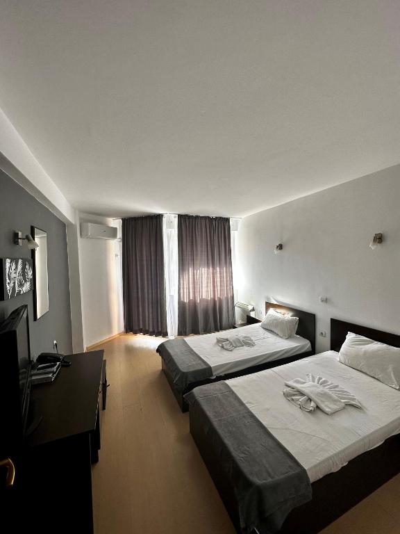 a hotel room with two beds and a television at Хотел Костенец in Kostenets
