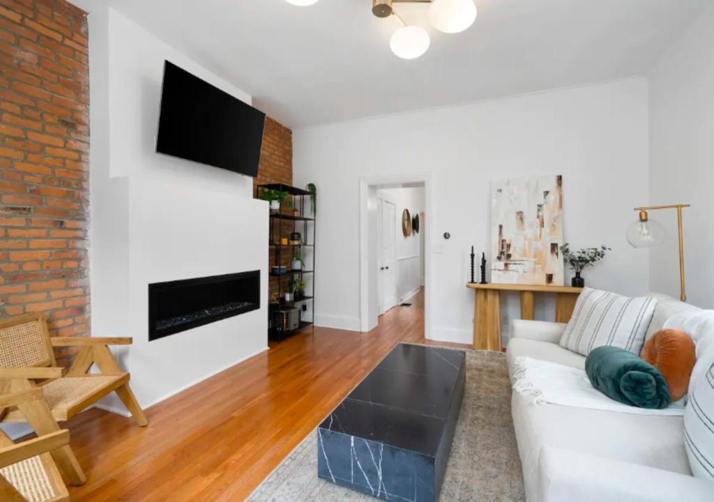 a living room with a white couch and a brick wall at Modern 3 Bed Apartment At Mid West in New York