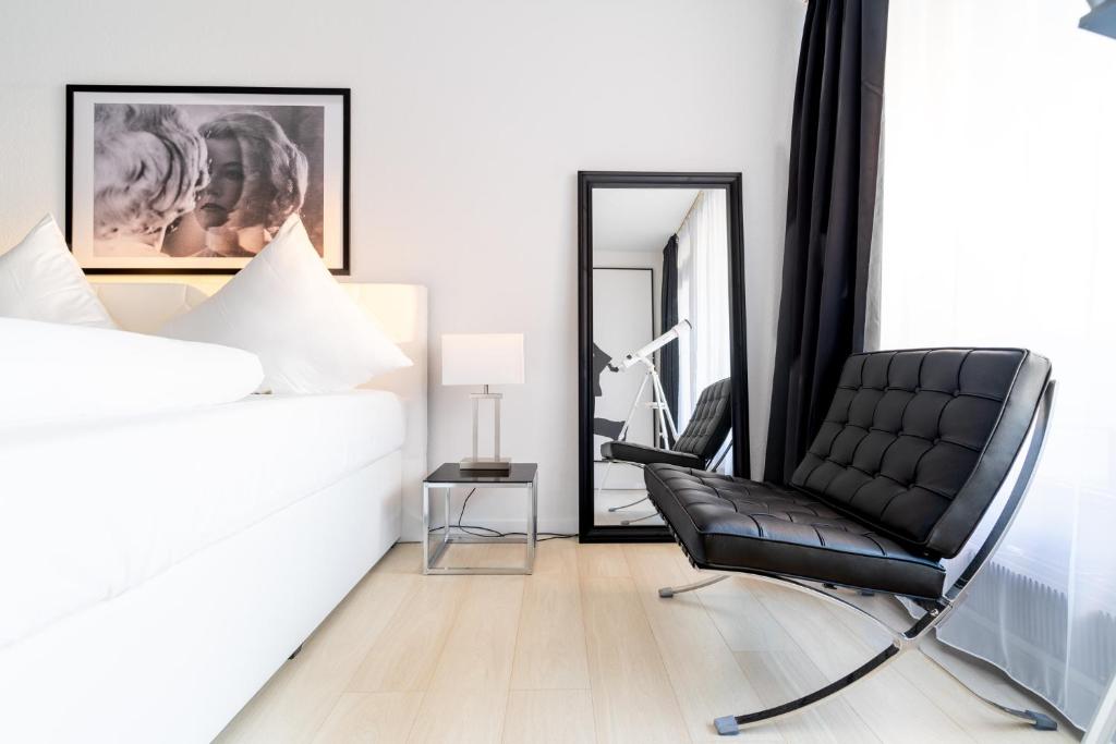 a black chair in a bedroom with a mirror at Beyond Living x American Psycho in Gelsenkirchen