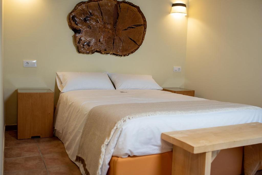 a bedroom with a bed with a large wooden clock on the wall at Pallozas Turísticas Ridicodias - A Vieira in Laza