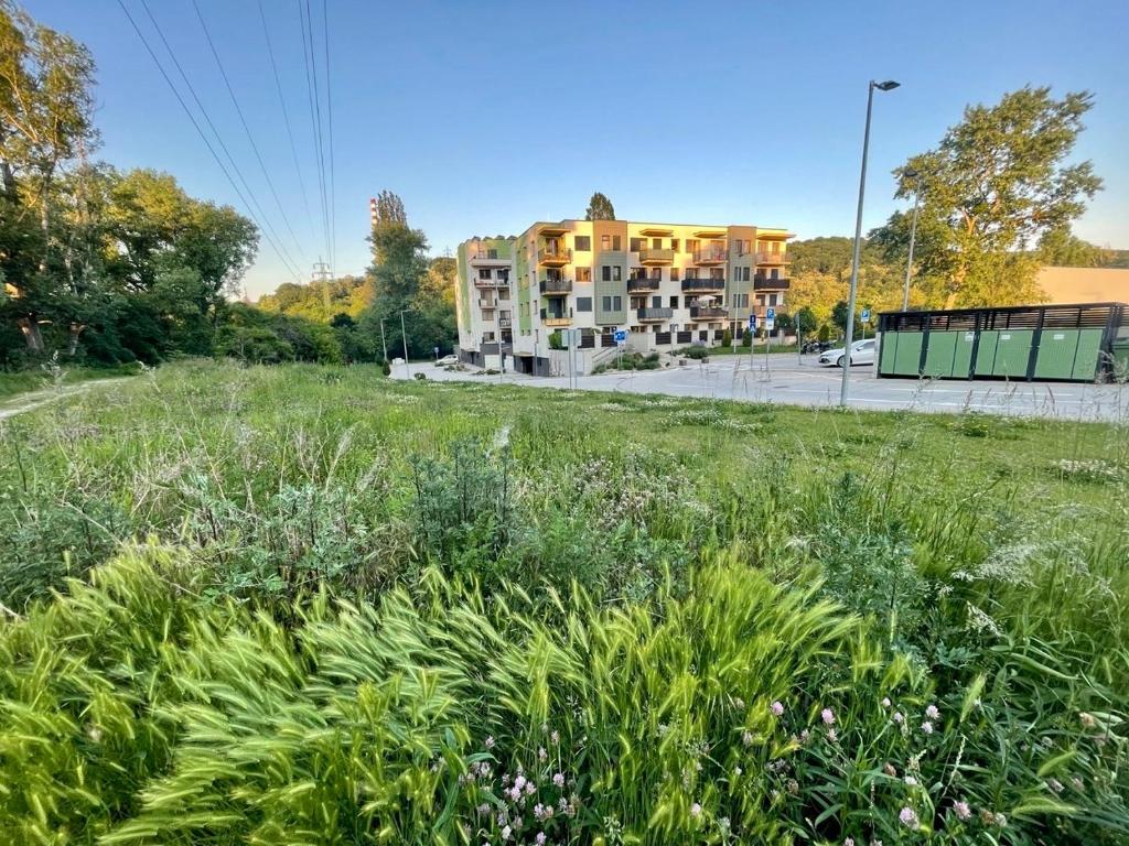 a field of grass in front of a building at Apartment Rosnička, Perfect Location with 24h Checkin, Balcony, AC & Free Parking in Bratislava