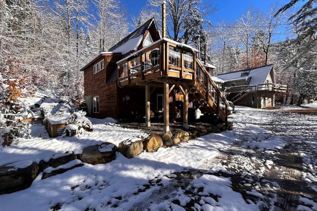 una cabaña de madera en la nieve con nieve en Sugarloaf Valley Escape, en Carrabassett
