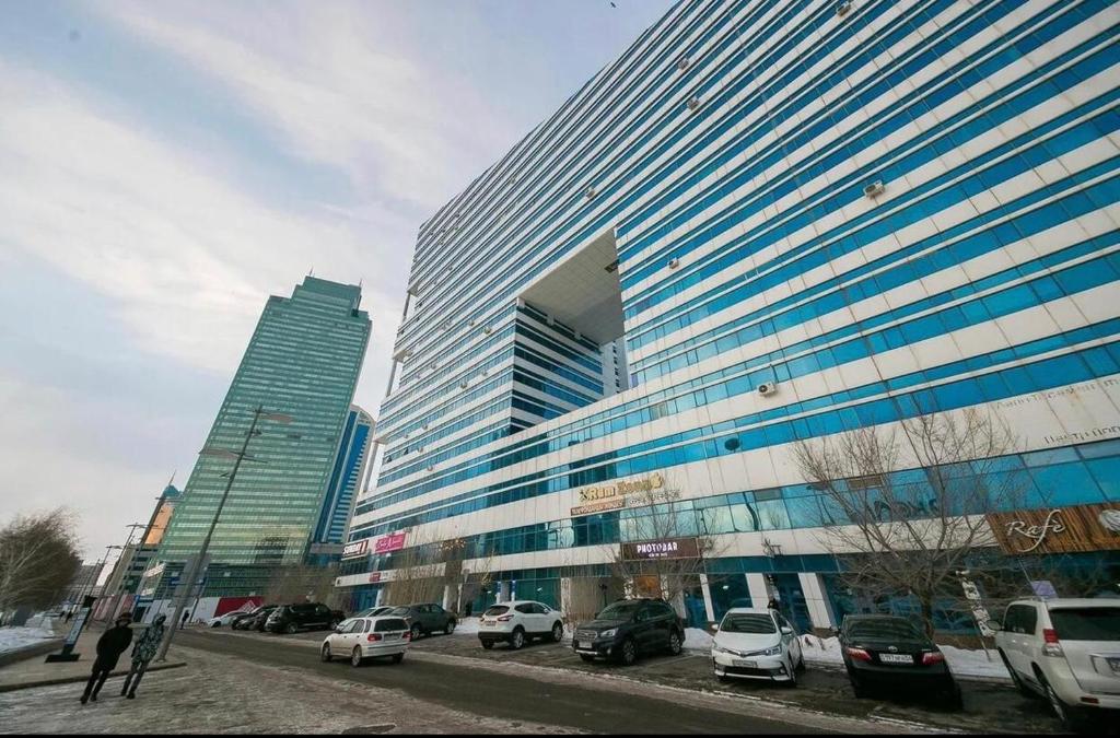 ein großes Gebäude mit Autos auf einem Parkplatz in der Unterkunft 4-х комнатная квартира in Astana