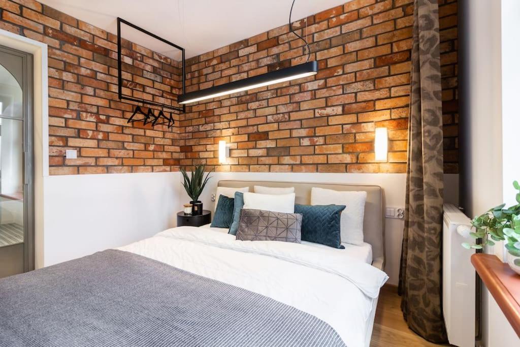 Un dormitorio con una pared de ladrillo y una cama. en Stylowy apartament nad Odrą, en Wroclaw