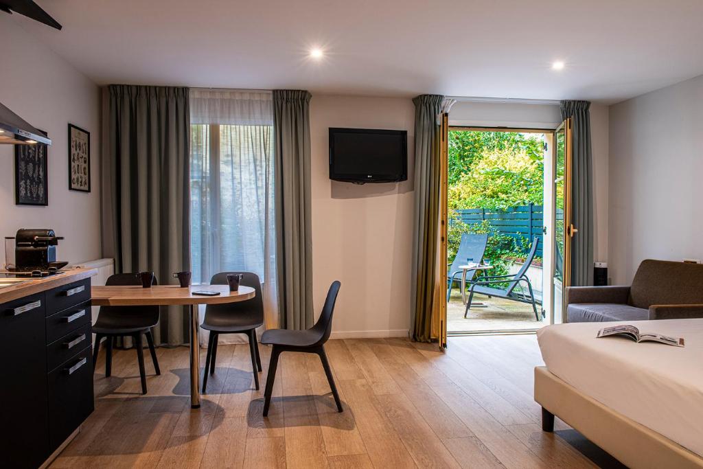 ein Hotelzimmer mit einem Tisch und einem Bett sowie einem Zimmer in der Unterkunft La Maison d'Eugène Appart'Hôtel - Centre Historique in Honfleur