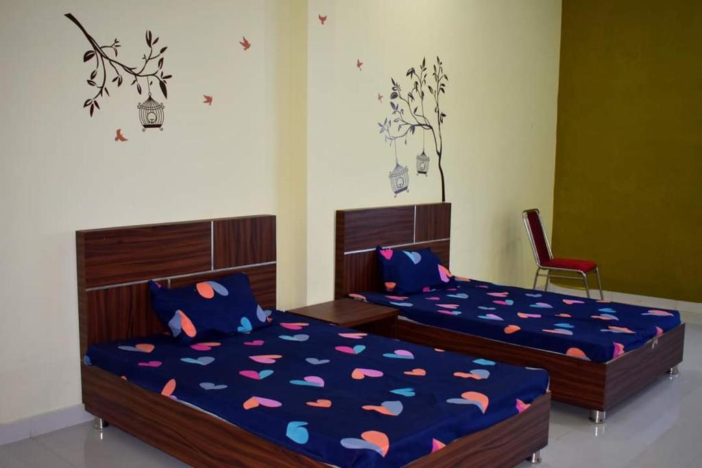 a bedroom with two beds and a red chair at HOTEL GS MARRIAGE GARDEN , KARELI in Karelī