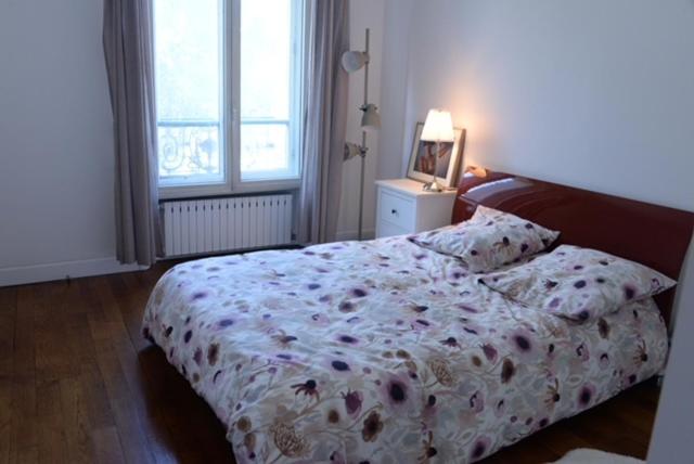 a bedroom with a bed with a flowered blanket at Eiffel Edge Escape in Paris