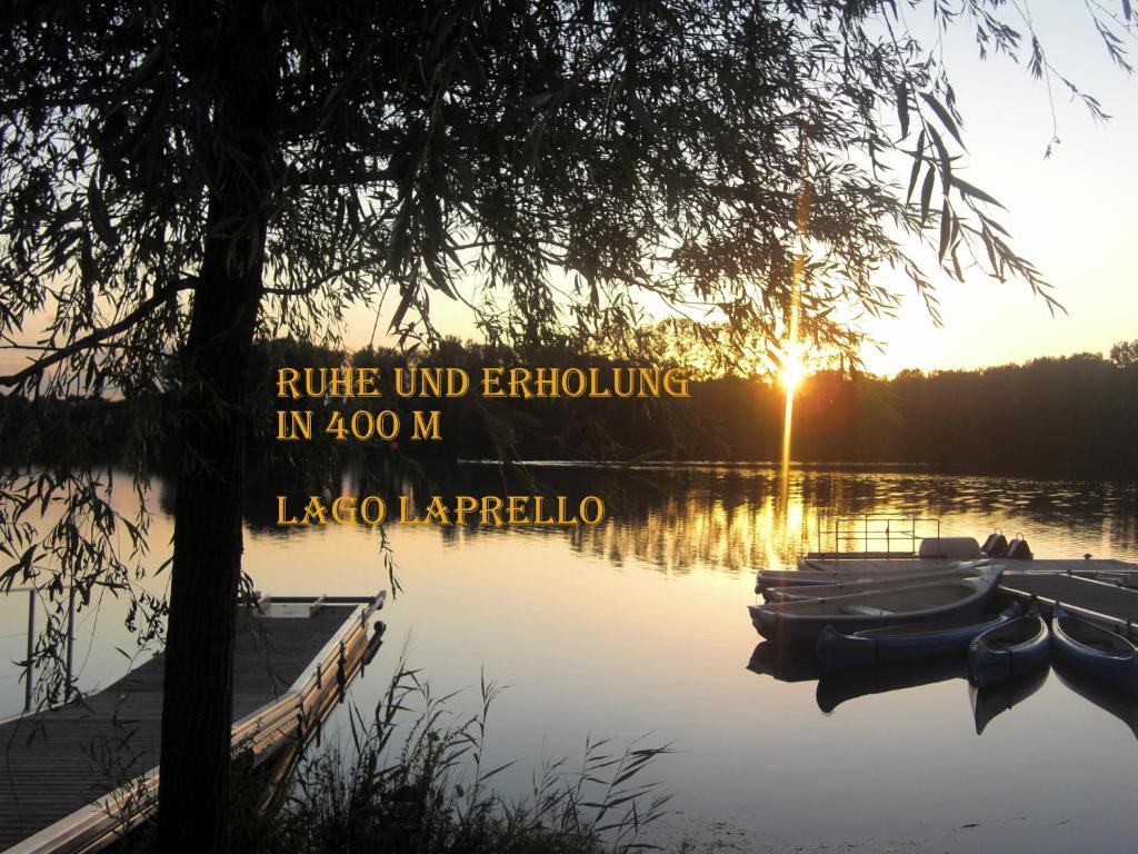 einen Sonnenuntergang auf einem See mit Booten im Wasser in der Unterkunft Ferienwohnung Casa Di Lago in Heinsberg
