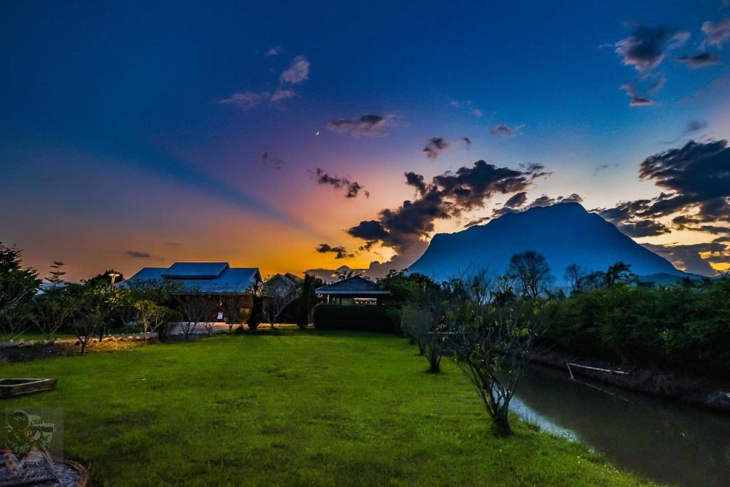 una puesta de sol con una montaña en el fondo y un campo de hierba en The Wes Village, incl Breakfast and Dinner en Chiang Dao