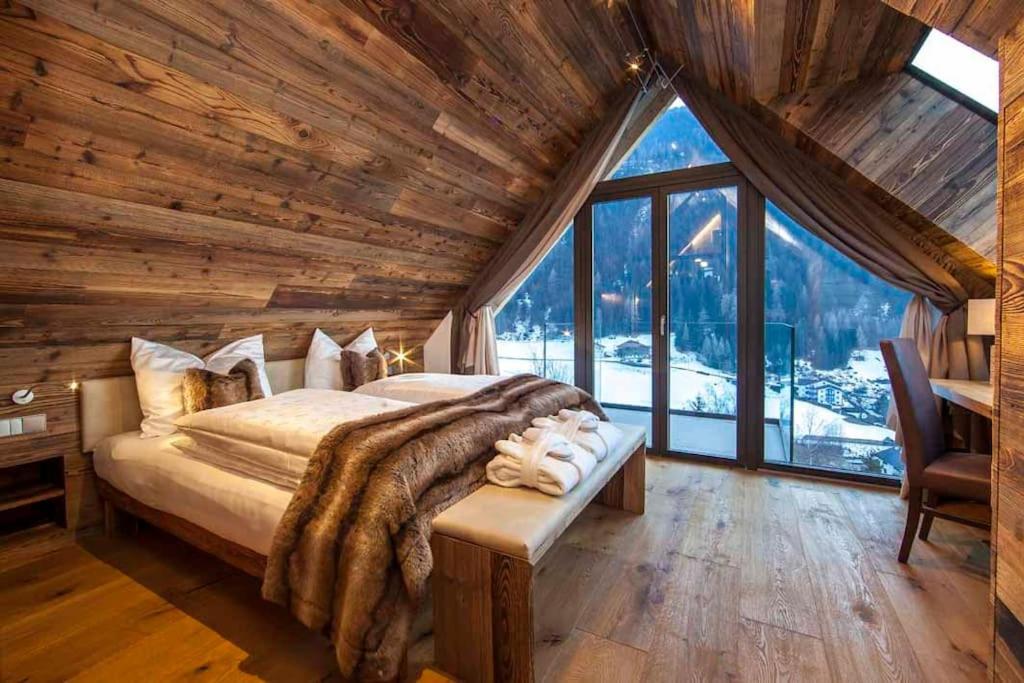 a bedroom with a large bed with a large window at Mountain Chalet Ghilga in Ortisei