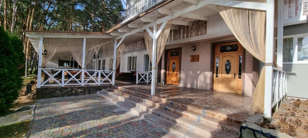 uma casa com um alpendre e portas de madeira em Готельно-Ресторанний Комплекс Три Бобри em Litowiż