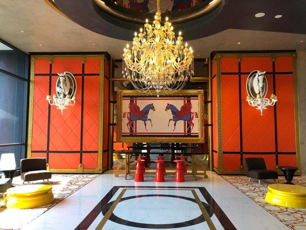 a lobby with a chandelier and a room with red walls at Arte Cheras Duplex Near MRT 1 in Kuala Lumpur