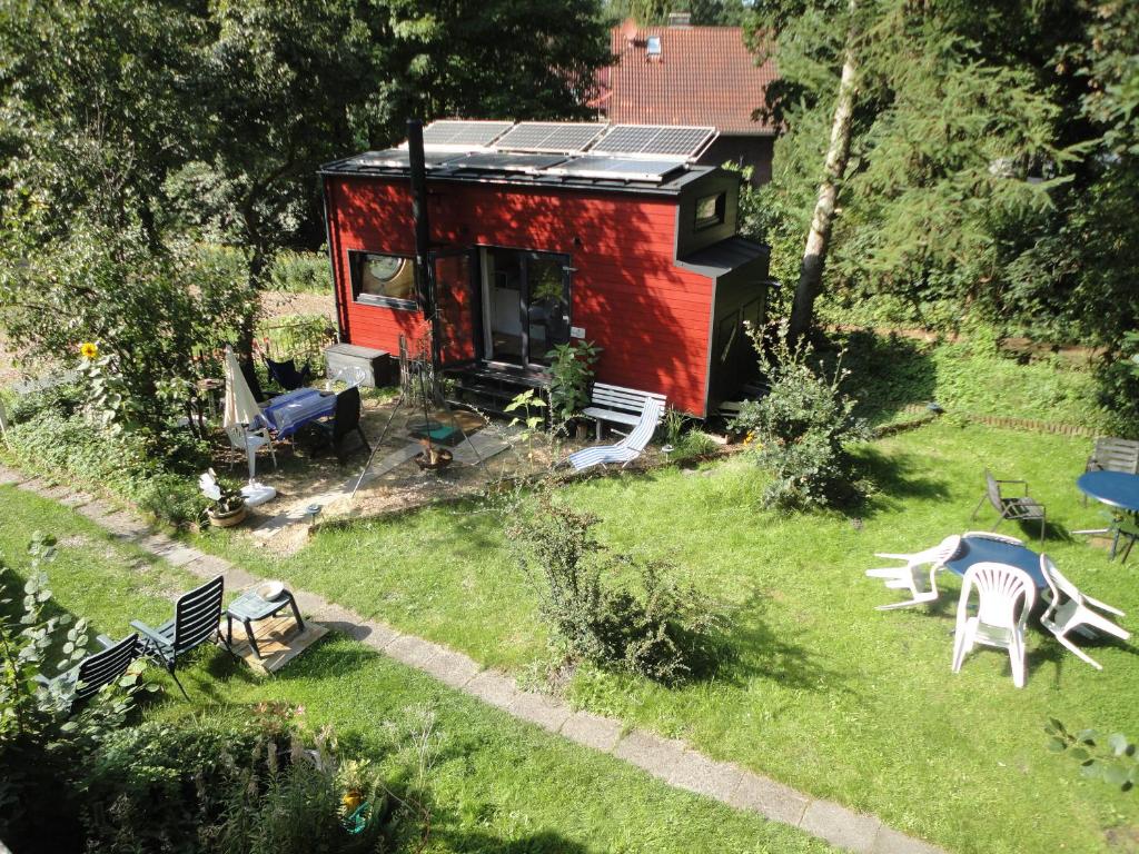een rood tiny house in een yard met banken bij Tinyhouse on wheels in Schortens