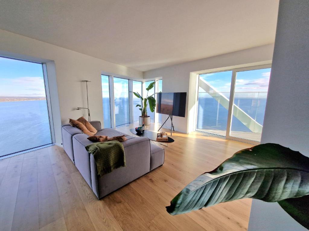 a living room with a couch and large windows at Tranquil apartment with panorama view over ocean above 20th floor in Aarhus