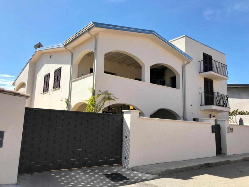 a white house with a black fence at Villa Bianca BB e Apartments in Àrbatax