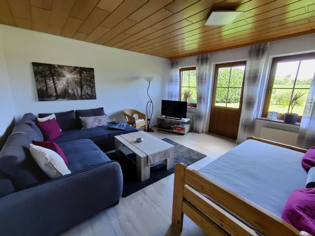 Komfort Ferienwohnung في Herscheid: غرفة معيشة مع أريكة زرقاء وطاولة