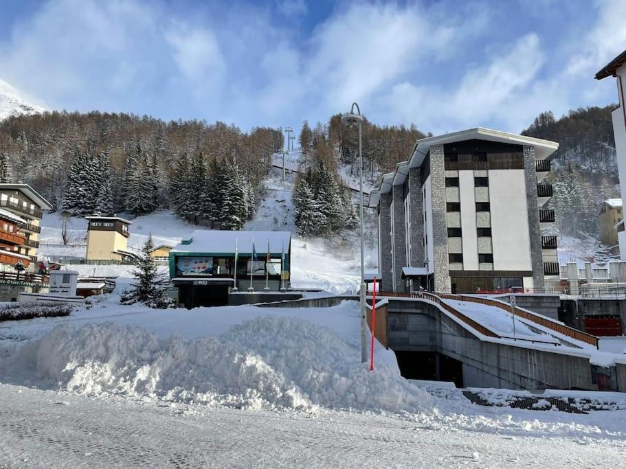 un rifugio da sci con un cumulo di neve accanto a un edificio di Casa Madesimo - Impianto sciistico e Parcheggio a Madesimo