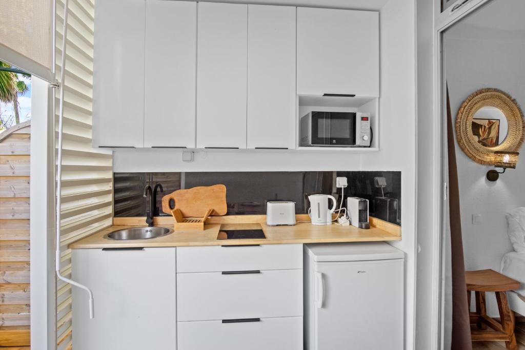 a kitchen with white cabinets and a sink at Studio Sunshine in Le Diamant