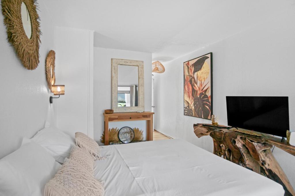 a white bedroom with a bed and a mirror at Studio Sunshine in Le Diamant