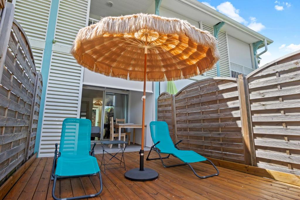 a patio with two chairs and an umbrella on a deck at Studio Sunshine in Le Diamant