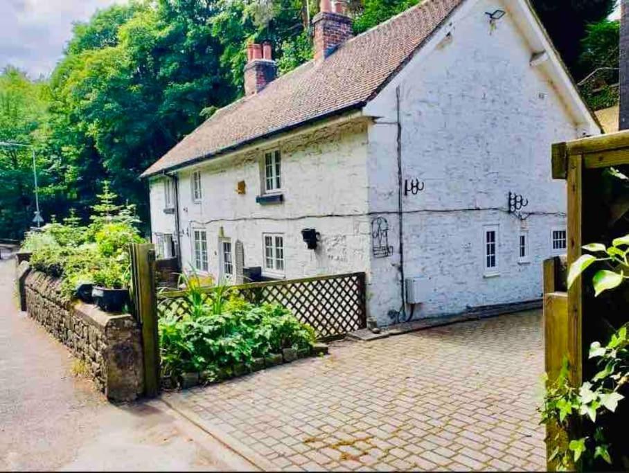 ein altes weißes Haus mit einer steinernen Einfahrt in der Unterkunft Dale Cottage 18th Century Country Cottage, 111 Barnston road in Heswall