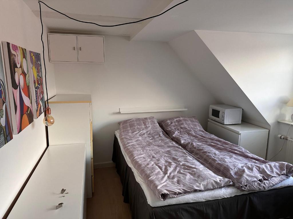 een bed in een kleine kamer met een witte muur bij Værelse i lejlighed med udsigt og ro in Aarhus
