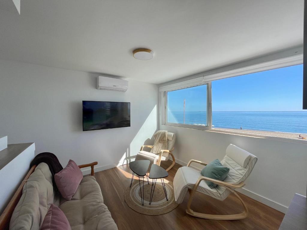 ein Wohnzimmer mit einem Sofa und Stühlen sowie einem großen Fenster in der Unterkunft Apartamento Calma Carihuela Beach - 10 metros de la playa in Torremolinos