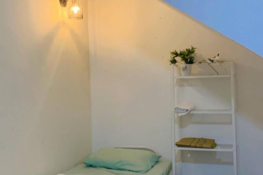 ein kleines Zimmer mit einem Regal und einem Bett in der Unterkunft Lily's HomeStay in Kulim