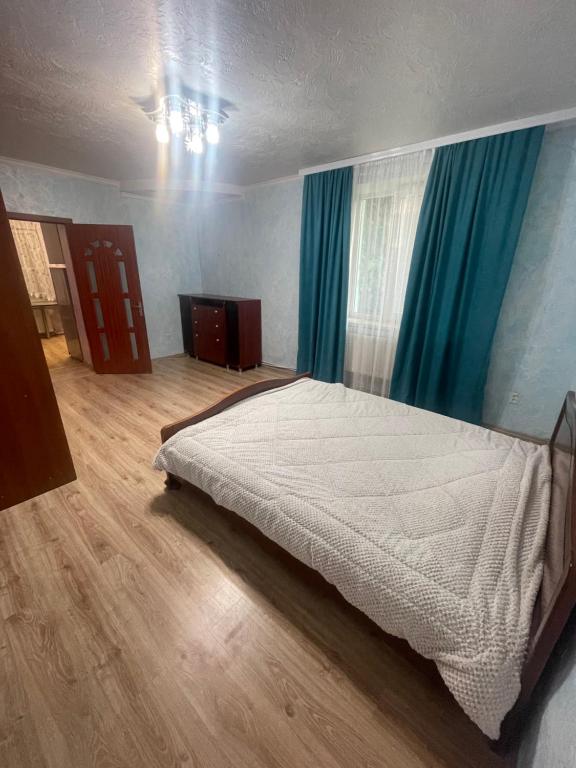 a bedroom with a large bed with blue curtains at Домик для гриль и отдыха Телецентр in Chişinău