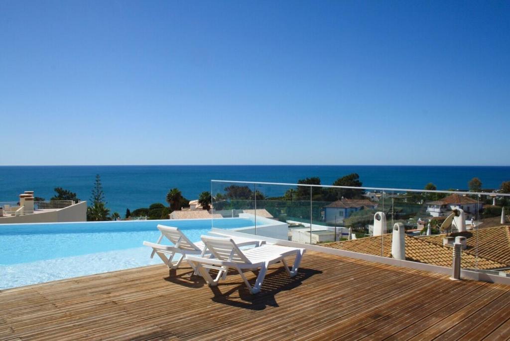 ein Swimmingpool mit zwei weißen Stühlen und einem Deck in der Unterkunft Blue Horizons, (AT18) 2 Bedroom, Olhos de Agua in Olhos de Água