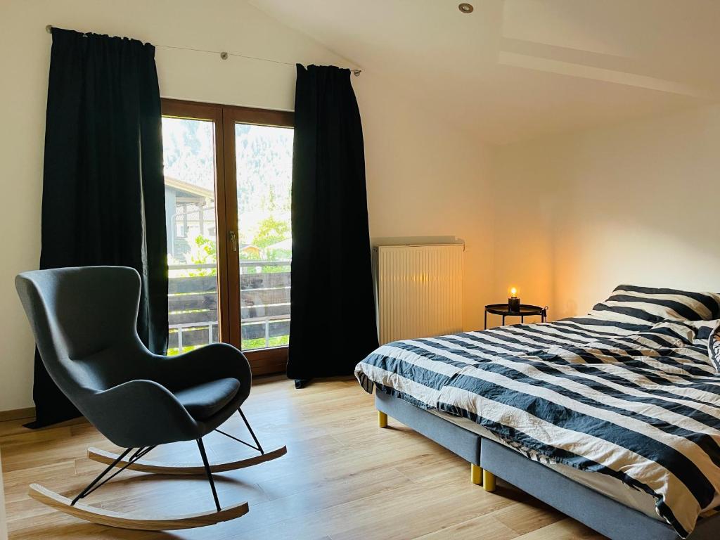 a bedroom with a bed and a chair and a window at Ferienhaus Bergrausch26 - Chiemgau Karte in Inzell