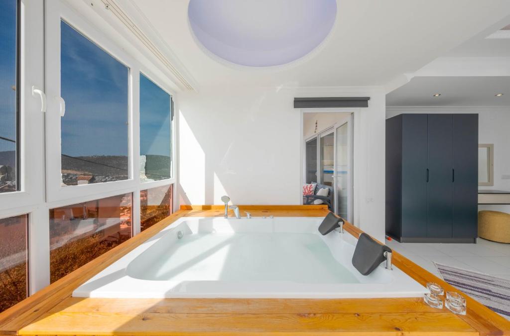 カシュにあるAren Guest House in Kalkanの大きな窓のある客室で、白い大型バスタブが備わります。