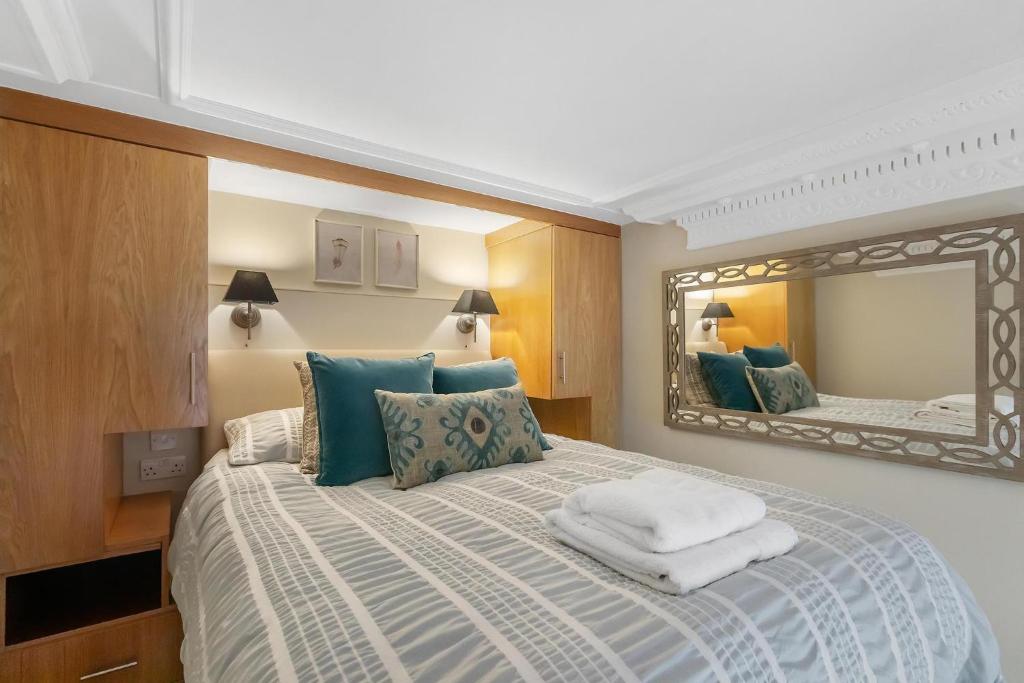 a bedroom with a bed with a large mirror at Stylish Kensington Apartments in London