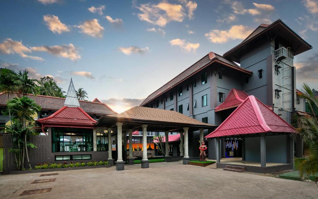 a large white building with red roof at Tuana Hotels The Phulin Resort in Karon Beach