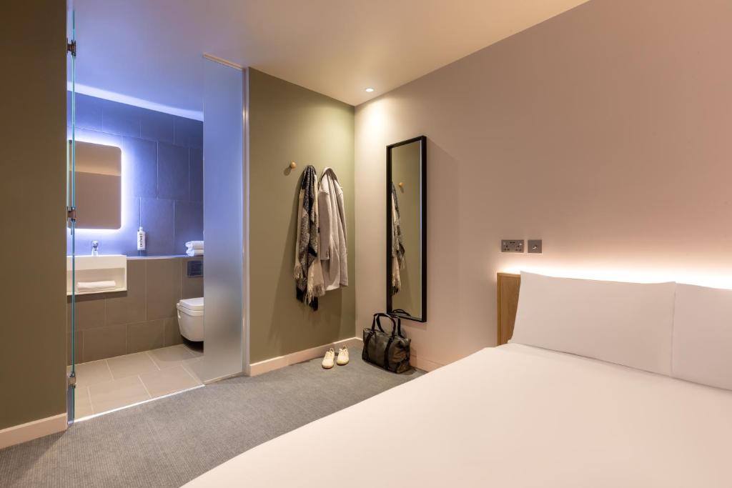 a bedroom with a large bed and a bathroom at Zedwell Greenwich in London