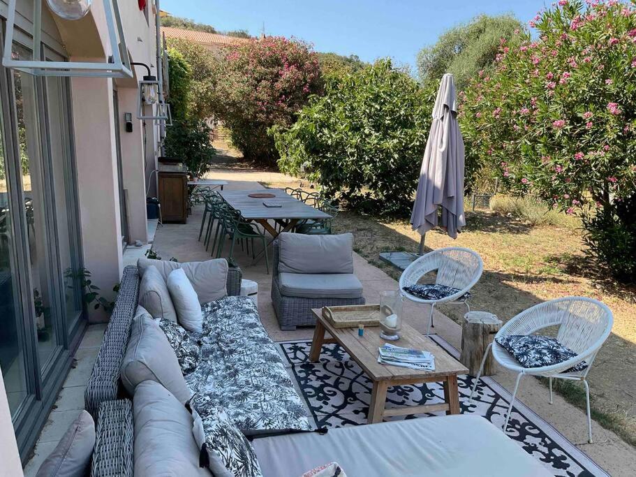 une terrasse avec un canapé, des tables et un parasol dans l'établissement Rez de chaussée villa avec piscine, à Piana