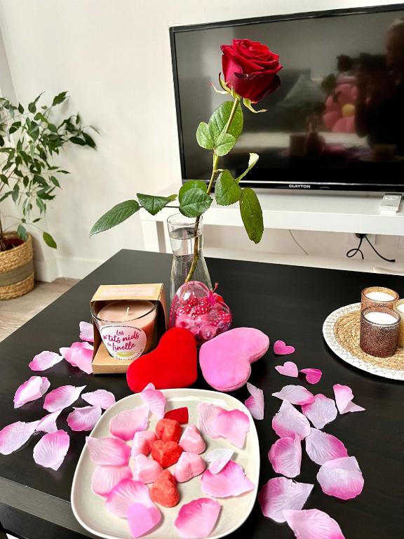 a table with a plate of flowers and a vase with a rose at Le Repaire du p&#39;tit Chartreux by LPNL in Rives