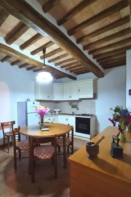 una cucina con tavolo in legno, sedie e frigorifero di Casa vacanze “La casetta di Anna” a Castel Viscardo