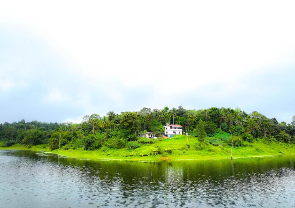 una casa en una colina junto a un cuerpo de agua en Karapuzha Homestay, en Meenangadi