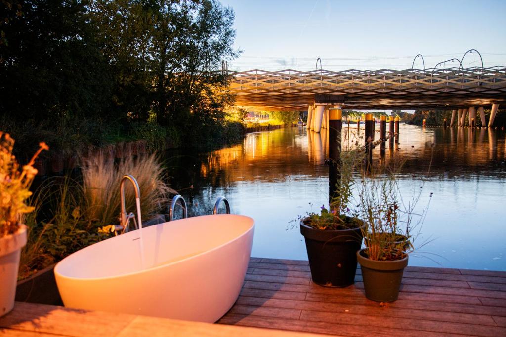 a bath tub sitting on a deck next to a river at Hoteldebootel 's-Hertogenbosch met prive sauna in Den Bosch