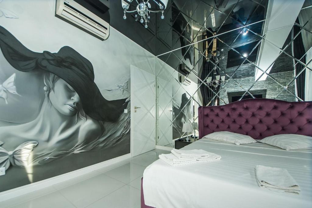 ガラツィにあるApartament Sweet Luxuryの帽子を被った女性の絵画が飾られたベッドルーム