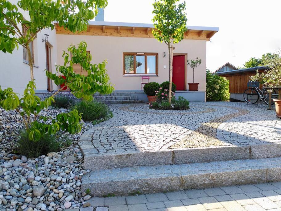 uma casa com um passadiço de pedra e uma porta vermelha em Bioappartement mit Garten, Waldnähe, Blick ins Inntal 100m em Simbach am Inn