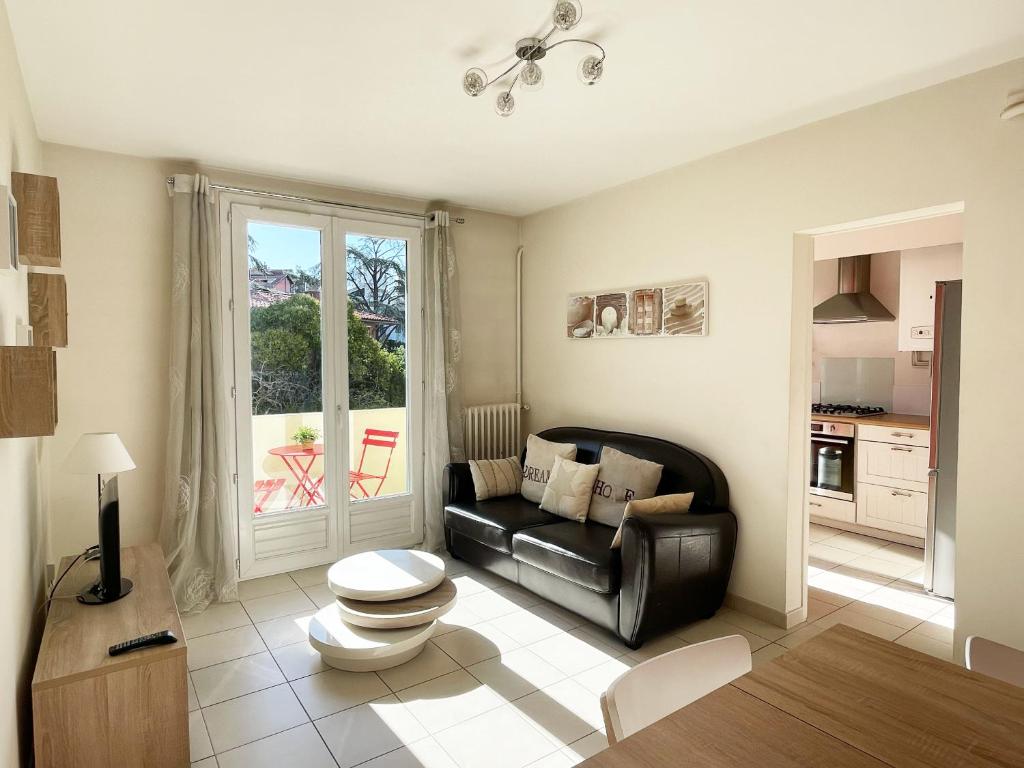 - un salon avec un canapé en cuir noir et une fenêtre dans l'établissement Toussaint by Yumē, à Toulouse