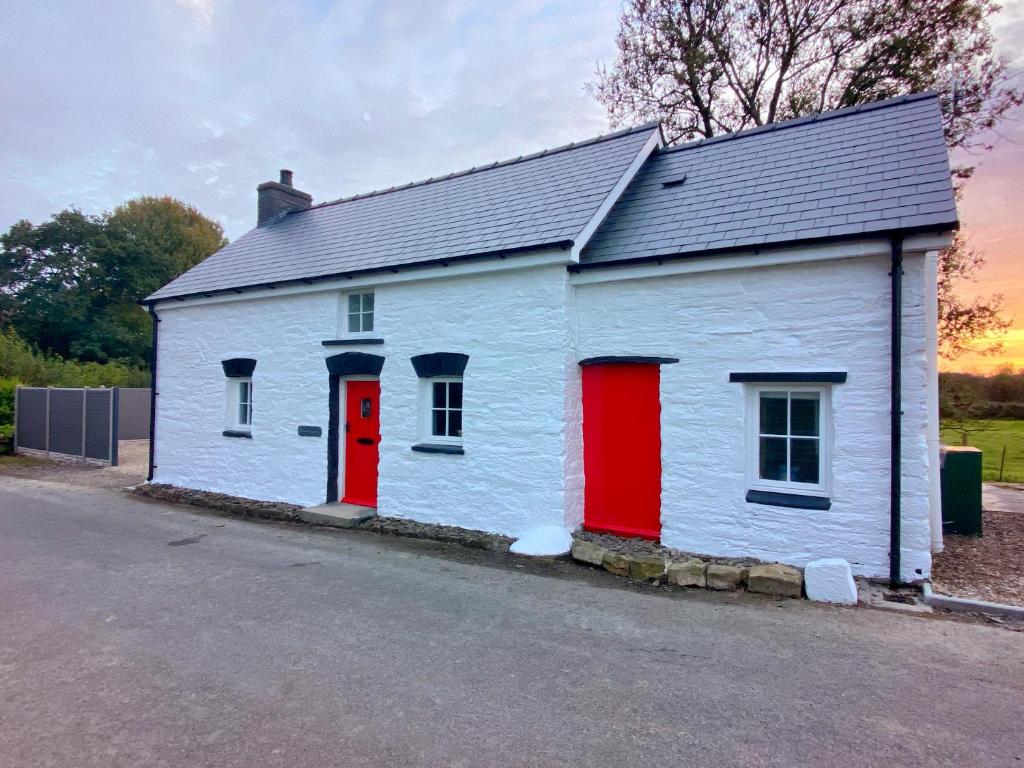 a small white building with red doors on a street at Pensarngerrig in Llandysul